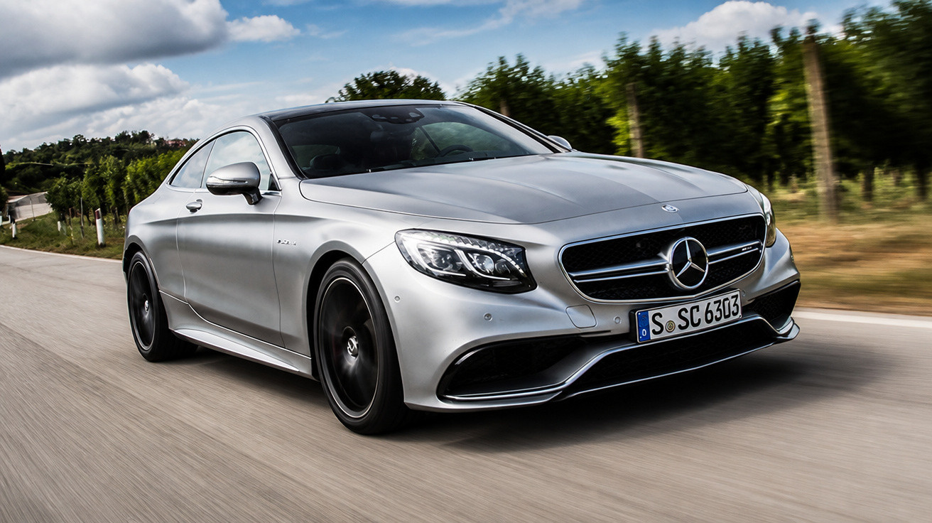 Carro desportivo Mercedes-Benz prata a circular numa estrada rodeada por árvores e vinhas.