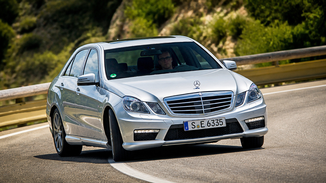 Carro Mercedes-Benz prata a contornar uma curva numa estrada de montanha durante o dia.